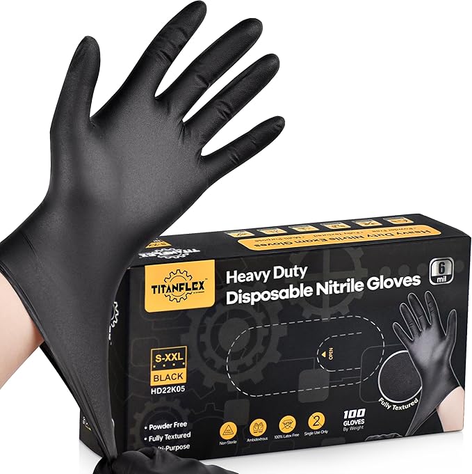 Black disposable nitrile glove held by a hand next to its packaging box on a white background