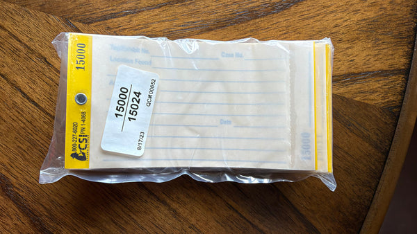 A packaged industrial part or pad shown in a clear plastic bag on a wooden surface. The top label is yellow with black text including '15000' and a visible 'CSI' logo, and a white sticker reads '15000 15024'.